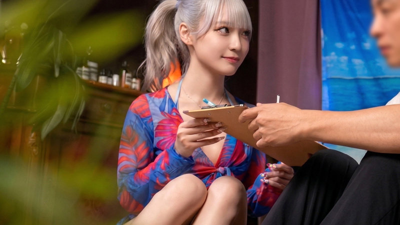 柄入りの長袖ビキニ姿で椅子に座り、男性からアンケート用紙を受け取る美菜の自然な表情