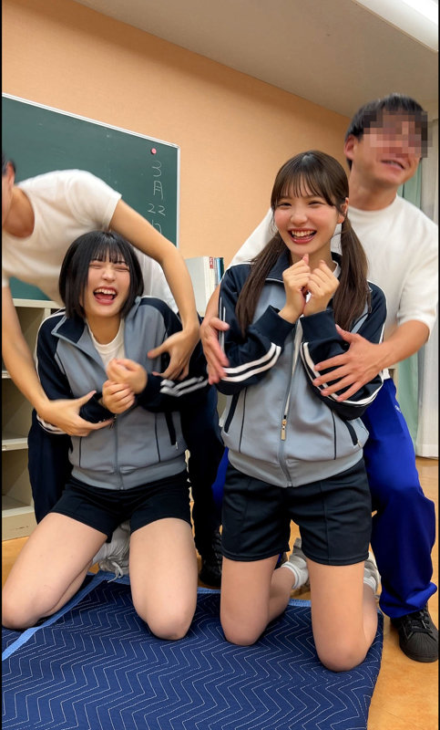 教室風の室内でジャージ姿の2人が男性に囲まれ、膝立ちで笑い合う明るい雰囲気のサンプルカット